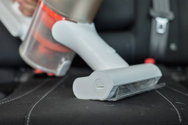 Kablosuz elektrikli süpürge, araba koltuğu döşemesini süpürüyor. Modern araba temizliği ve bakımı
