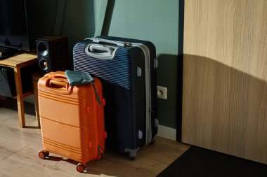 İki modern bavul, turuncu ve lacivert, sabah ışığında giriş kapısının yanında durun. Oturma odasındaki bavullar tatil için hazır. Seyahat hazırlığı kavramı