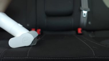 Kablosuz elektrikli süpürge, araba koltuğu döşemesini süpürüyor. Modern araba temizliği ve bakımı