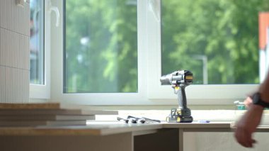 Marangozun işe hazırlandığı, matkap ve koruyucu eldiven aldığı yakın plan çekimleri. Mobilya montaj konsepti