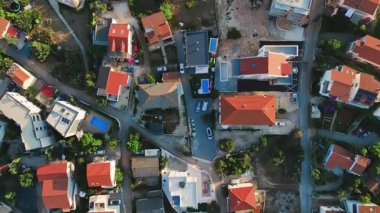 Akdeniz kıyısı manzaralı villaları, yüzme havuzları ve park edilmiş arabaları olan bir yer. Bir sahil kasabasında yazlık evler