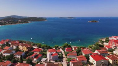 Arka planda deniz olan yerleşim yerinin havadan görüntüsü. Yaz mevsiminde Adriyatik sahil kasabası. Akdeniz kıyısında yaz tatili için villaları olan kıyı köyü.