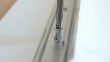 Mobilya veya dolap montajı sırasında metal korkulukları takmak için tornavidayı tahta tahtaya sürerken makro çekim