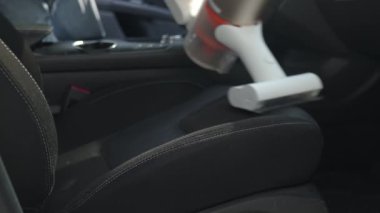 Araba koltuğunu elektrikli süpürgeyle temizliyorum.