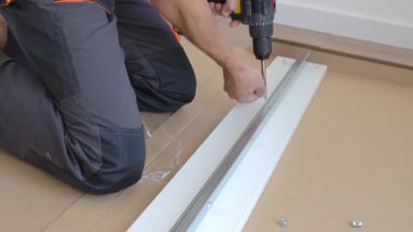 Mobilya montajı sırasında metal ray kurmak için tornavida kullanan işçiler