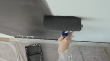 Ev tadilatı sırasında elektrik prizlerinin yakınındaki duvarı siyaha boyamak için silindir kullanan kişinin ayrıntılı görüntüsü
