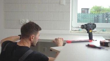 Adam kurulum sırasında mutfak tezgahı panelini hizalamak için ruh seviyesini kullanıyor. Yeni evdeki yenileme sırasında profesyonel mutfak mobilyası montajı