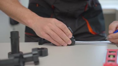 İnsan mutfak dolapları sırasında mobilya parçalarını ölçer, mezura, aletler ve plastik mobilya bacakları kullanır.