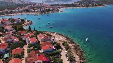 Arka planda deniz olan yerleşim yerinin havadan görüntüsü. Yaz mevsiminde Adriyatik sahil kasabası. Akdeniz kıyısında yaz tatili için villaları olan kıyı köyü.
