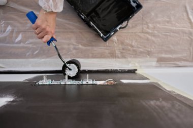 Ev tadilatı sırasında elektrik prizlerinin yakınındaki duvarı siyaha boyamak için silindir kullanan kişinin ayrıntılı görüntüsü