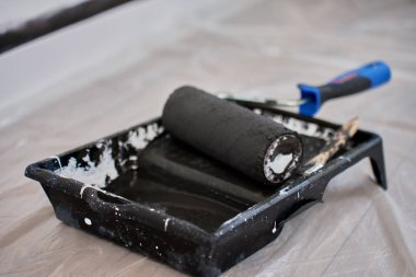 İç boyama işlemi sırasında koruyucu filme siyah boya ile doldurulmuş siyah boya rulosu. Ev tadilatı sırasında duvar boyama hazırlığı