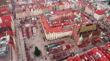 Wroclaw Noel pazarının havadan görünüşü dekore edilmiş tezgahlar, atlıkarınca ve tarihi binalar. Renkli Avrupalı eski kasaba meydanında bayram havası