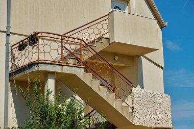 Beton merdiven, bej konutta dekoratif metal korkuluklar. Dışarıdaki merdivenlerin mimari detayları.