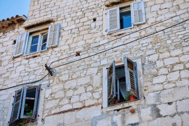 Açık cam pencereli ve tahta panjurlu eski bir ev. Bina cephesi. Otantik Akdeniz mimarisi