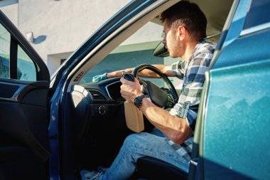 Adam arabanın ön panelini mikrofiber bez ve sprey şişeyle temizliyor. Otomobil bakımı, araba dezenfeksiyonu ve araba hijyeni kavramı