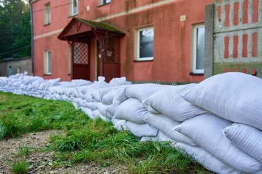 Su baskınına karşı korunmak için bina dışına istiflenmiş kum torbaları. Acil sel önleme ve konut evinin yakınındaki koruyucu su bariyeriyle doğal afet hazırlığı kavramı