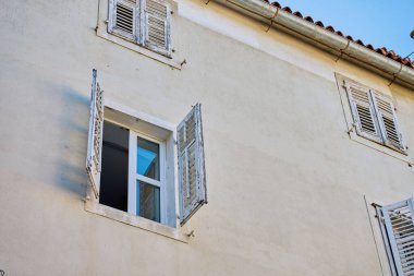 Açık cam pencereli ve tahta panjurlu eski bir ev. Bina cephesi. Otantik Akdeniz mimarisi