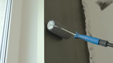 İç yenileme sırasında duvara koyu renk uygulayan boya silindirinin yakın çekimi. DIY boya kavramı, ev dekorasyonu ve modern apartmanda yeniden dekorasyon