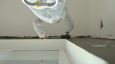 İç dekorasyon sırasında duvar ve tavanı siyah renkli boyayla boyamış koruyucu elbiseli bir kadın.