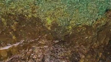 Şeffaf turkuaz suyun havadan görünüşü kayalık deniz yatağının üzerinde. Dalgalanan deniz yüzeyinde uçmak