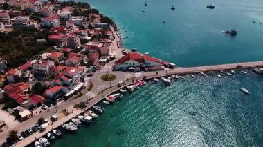 Güneşli bir günde geleneksel evleri, balıkçı tekneleri ve marinası olan kıyı kasabasının havadan görünüşü. Akdeniz manzarası ve denizde bir ada. Turizm ve yaz seyahati kavramı