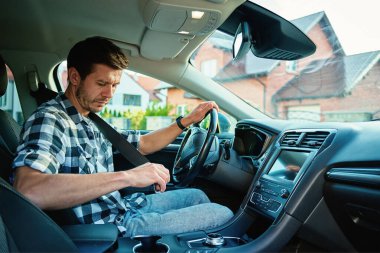 Modern arabanın içinde emniyet kemeri takan adam sürmeye hazırlanıyor. Yol güvenliği ve sorumlu sürüş kavramı