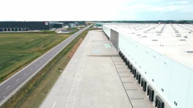 Lojistik deposunun dış tarafındaki yükleme platformlarının havadan görüntüsü. Dağıtım merkezinde kamyon ambarları ve kapalı yükleme kapıları. Nakliye işlemleri için ticari altyapı