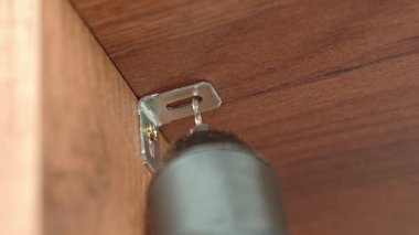 Metal parantez için elektrikli matkap kullanarak ahşap mobilya delme deliğini kapatın. Ahşap gardırop montajı. DIY mobilya montajı kavramı