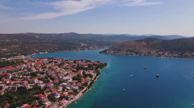 Adriyatik Denizi kıyısında sakin mavi suları, tekneleri ve etrafındaki dağlarla manzaralı bir kasaba. Akdeniz kıyı şeridinin panoramik hava görüntüsü