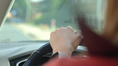 Güneşli yolda araba sürerken direksiyon tutan kadının arka manzarası. Araçtaki kadın sürücü. Özgürlük, seyahat ve yolculuk kavramı