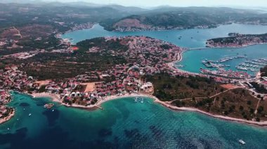 Adriyatik Denizi kıyısında sakin mavi suları, tekneleri ve etrafındaki dağlarla manzaralı bir kasaba. Akdeniz kıyı şeridinin panoramik hava görüntüsü