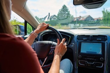 Ekranda GPS navigasyonu olan, elleri direksiyonda olan modern araba kullanan bir kadın. Modern seyahat, yolculuk ve akıllı araç teknolojisi kavramı