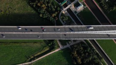 Yeşil tarlalarla çevrili otoban köprüsünün havadan görünüşü. Ulaşım ve modern yol altyapısı kavramı