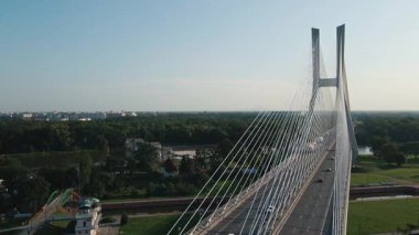 Çağdaş kablo destekli köprü manzarası geniş nehir üzerinde araçlar ve yeşil manzarayla çevrili baraj ve kilit sistemi. Ulaşım ve mimari altyapı kavramı