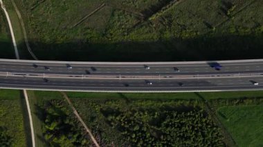 Yeşil tarlalarla çevrili otoban köprüsünün havadan görünüşü. Ulaşım ve modern yol altyapısı kavramı
