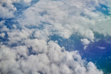 Beyaz kabarık bulutların uçak penceresinden gökyüzünde yüzen dağlar ve nehirler.