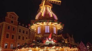 Christmas fair at night with illuminated gifts and festive carousel in historic city center. Festive Christmas market in Wroclaw, Poland. Concept of holiday celebration, winter tradition and tourism