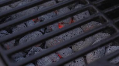 Izgarada ızgaranın altında kızaran kömür kömürlerinin yakın çekimi pişirmeye hazır. Yaz mangalı, açık hava aktivitesi ve piknik hazırlığı konsepti.