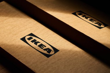 IKEA karton ambalaj kutularına yakın çekim ve güneş ışığı altında marka logosu. Ev mobilyası montajı. Wroclaw, Polonya - 25 Mayıs 2025