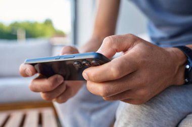 Akıllı telefon kullanan adam, kapat. Erkek eller akıllı telefonu tutuyor ve dışarıda oyun oynuyorlar. Teknoloji kavramı, dijital eğlence ve alet kullanımı