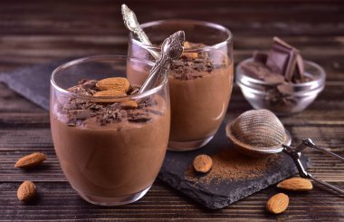 Koyu ahşap arka planda badem kaplı çikolatalı mus..