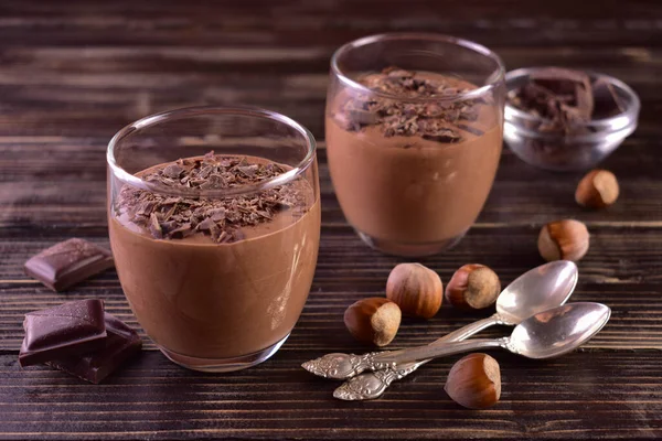 stock image Mousse with dark chocolate with hazelnuts in glasses on a dark wooden background.