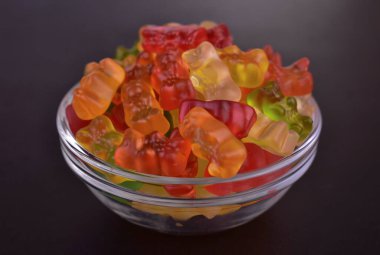 Birçok renkli jöle ayıcığı siyah arka planda bir tabakta. Yakın plan..