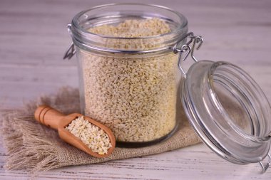 Tahta bir arka planda kavanozdaki beyaz susam tohumları. Yakın plan..