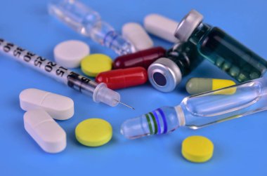 Medicines on a blue background: injection ampoules tablets and syringes.
