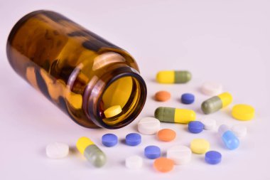 Multicolored pills in a pill bottle on a white background