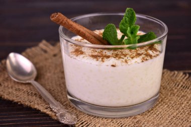  Rice pudding with cinnamon in a glass on a dark wooden background.Close-up.