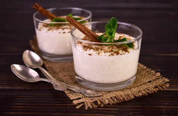 Rice pudding with cinnamon in glasses on a dark wooden background.