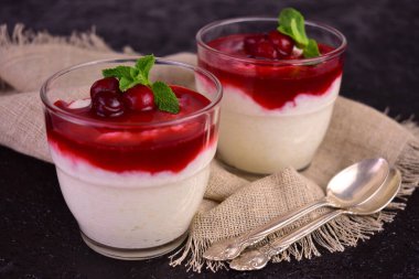 Delicate rice pudding with sweet and sour cherry jam on a black background.