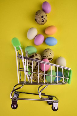 Easter eggs in a shopping basket on a yellow background.